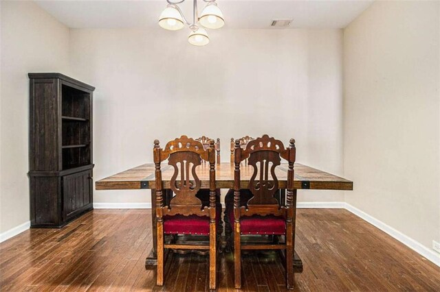 dining area featuring dark wood-type flooring and an inviting chandelier