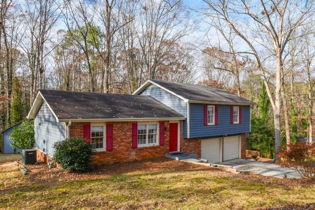 split level home with central AC unit, a garage, and a front lawn