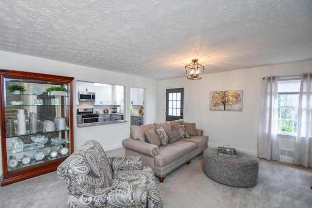 carpeted living room with a chandelier and a textured ceiling