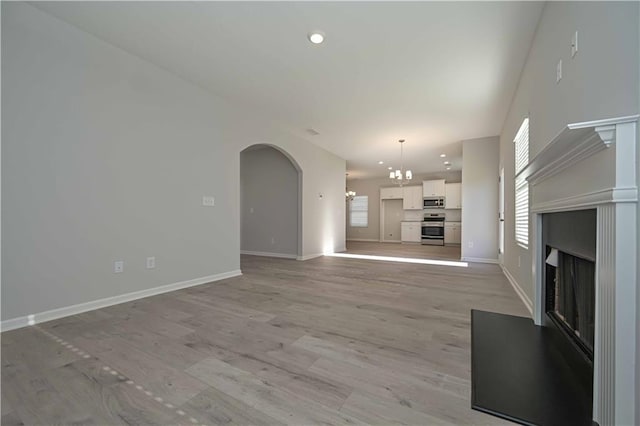 unfurnished living room with a chandelier and light hardwood / wood-style floors