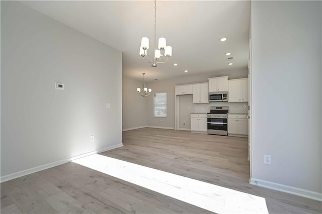 kitchen featuring an inviting chandelier, light wood-type flooring, appliances with stainless steel finishes, decorative light fixtures, and white cabinetry