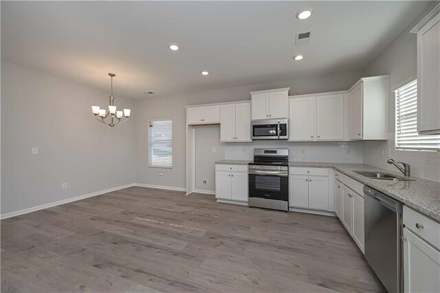 kitchen featuring white cabinets, sink, light stone countertops, light wood-type flooring, and stainless steel appliances