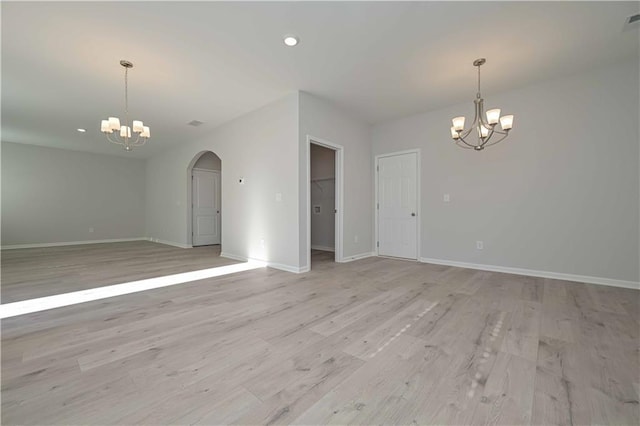 unfurnished room with a notable chandelier and light wood-type flooring