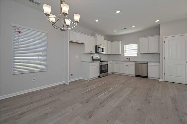 kitchen featuring hanging light fixtures, appliances with stainless steel finishes, tasteful backsplash, white cabinetry, and a chandelier