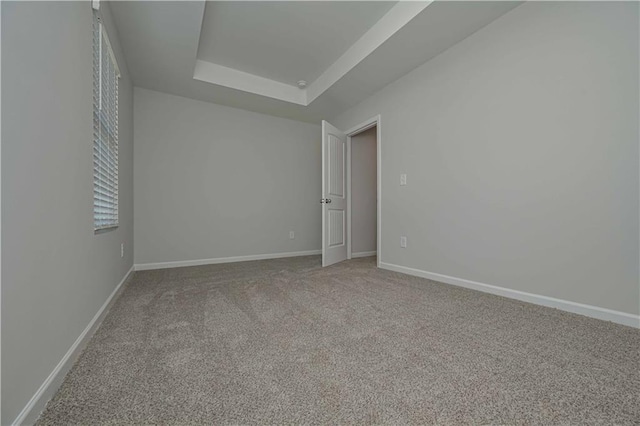 carpeted spare room with a raised ceiling