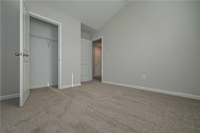 unfurnished bedroom with carpet, a closet, and vaulted ceiling