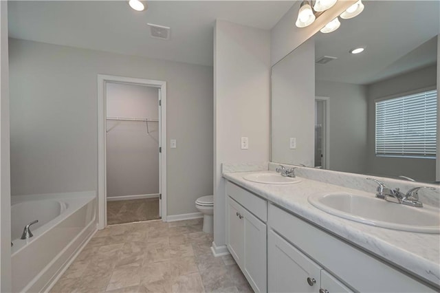 bathroom featuring vanity, a tub to relax in, and toilet