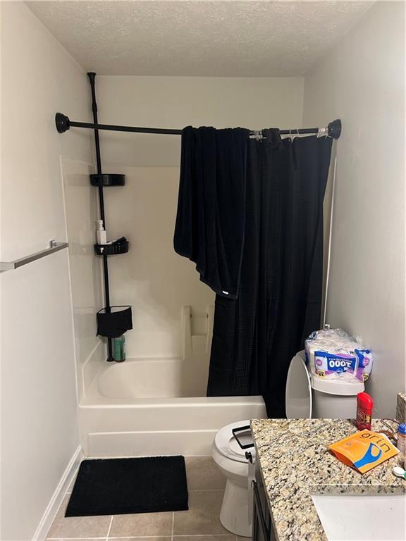 122 Sterling Ct Unit 122, Alpharetta, GA 30004 - bathroom with a textured ceiling, tile patterned floors, toilet, vanity, and shower / bathtub combination with curtain