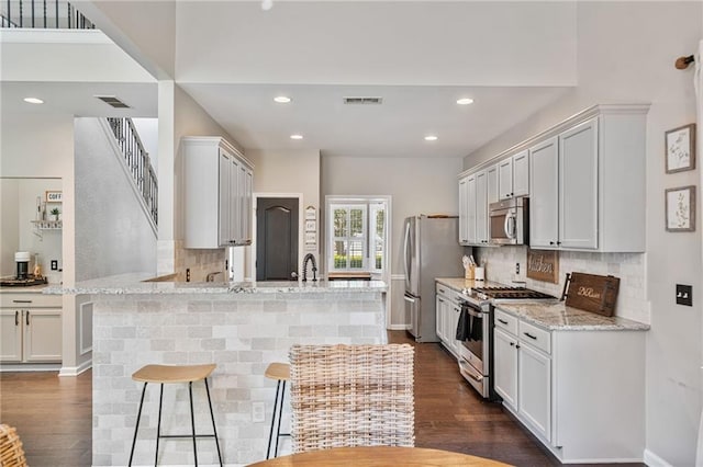 217 Springs Xing, Canton, GA 30114 - kitchen with stainless steel appliances, dark wood finished floors, a peninsula, decorative backsplash, and light stone countertops