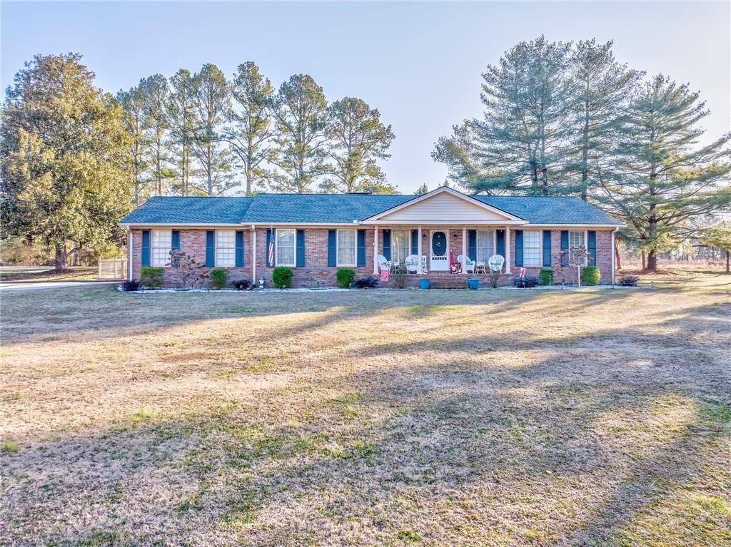 ranch-style home featuring covered porch and a front lawn