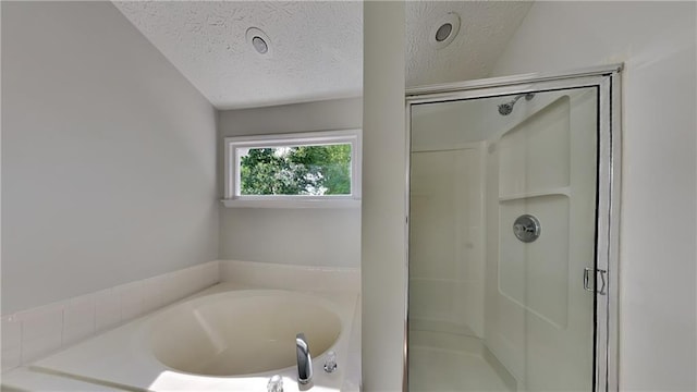 bathroom featuring a shower stall, a garden tub, and a textured ceiling