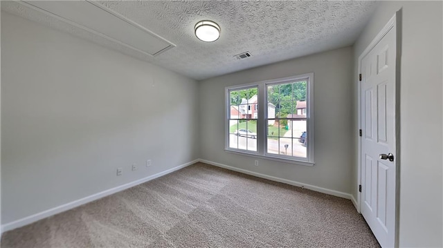 empty room featuring attic access, carpet flooring, baseboards, and a textured ceiling