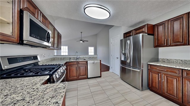 kitchen with appliances with stainless steel finishes, a sink, vaulted ceiling, a ceiling fan, and glass insert cabinets