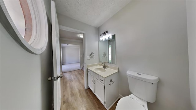 bathroom with wood finished floors, toilet, a textured ceiling, and vanity
