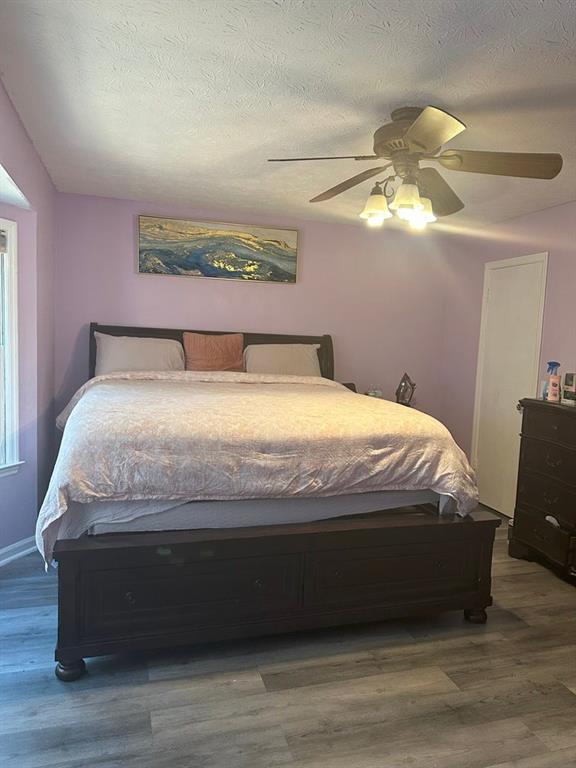 bedroom with ceiling fan, a textured ceiling, and hardwood / wood-style flooring