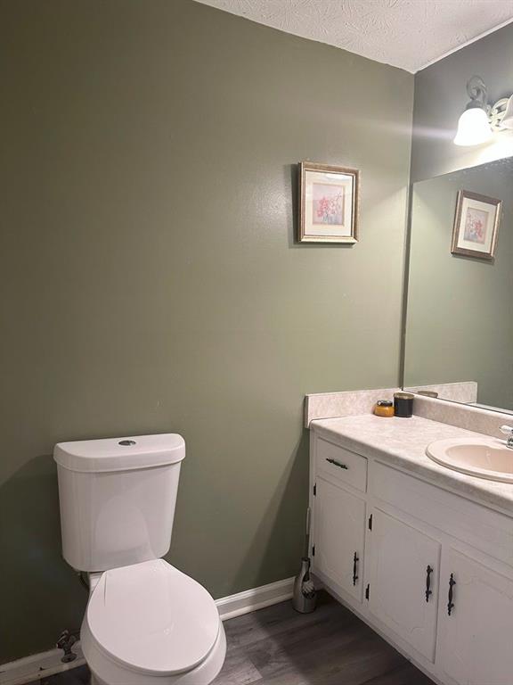 bathroom featuring vanity, toilet, wood-type flooring, and a textured ceiling