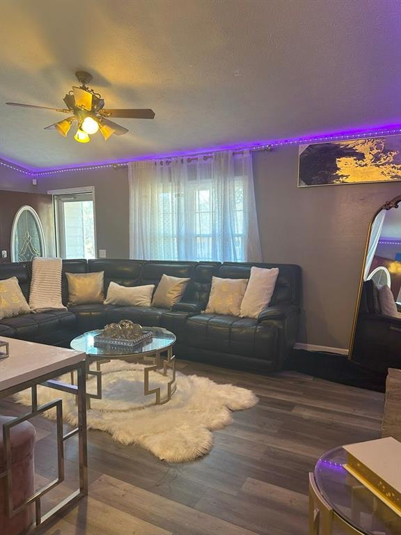 living room featuring hardwood / wood-style flooring, ceiling fan, and a textured ceiling