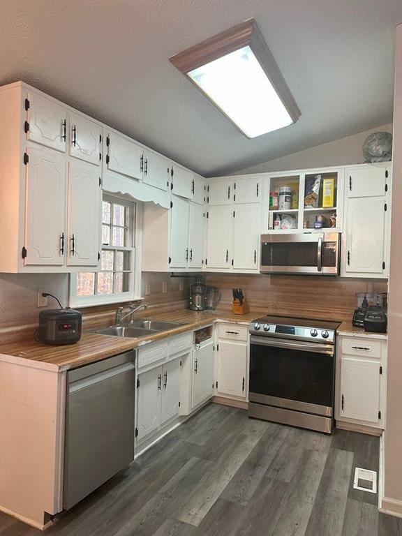 kitchen featuring sink, stainless steel appliances, lofted ceiling, decorative backsplash, and white cabinets