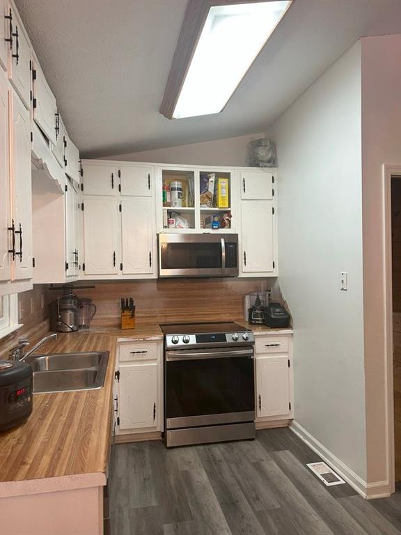 kitchen with decorative backsplash, stainless steel appliances, vaulted ceiling, sink, and white cabinetry