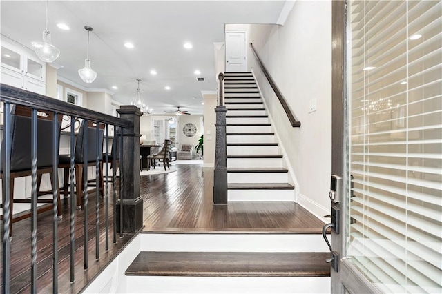 stairs with ceiling fan, wood-type flooring, and ornamental molding