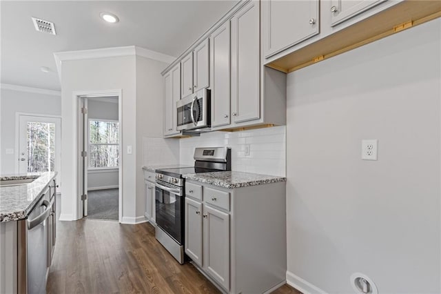 kitchen featuring dark wood finished floors, baseboards, appliances with stainless steel finishes, light stone countertops, and visible vents