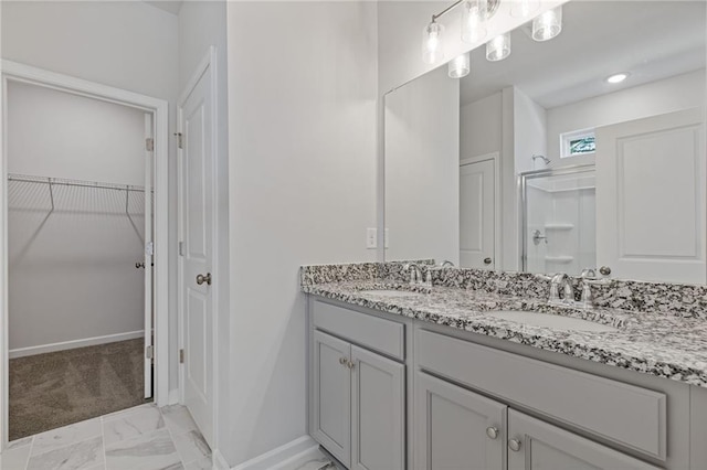 bathroom featuring marble finish floor, baseboards, a sink, and a stall shower