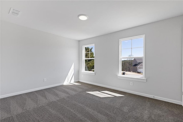 empty room featuring baseboards, dark colored carpet, and visible vents
