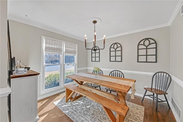 dining area featuring dark wood-type flooring, an inviting chandelier, and ornamental molding