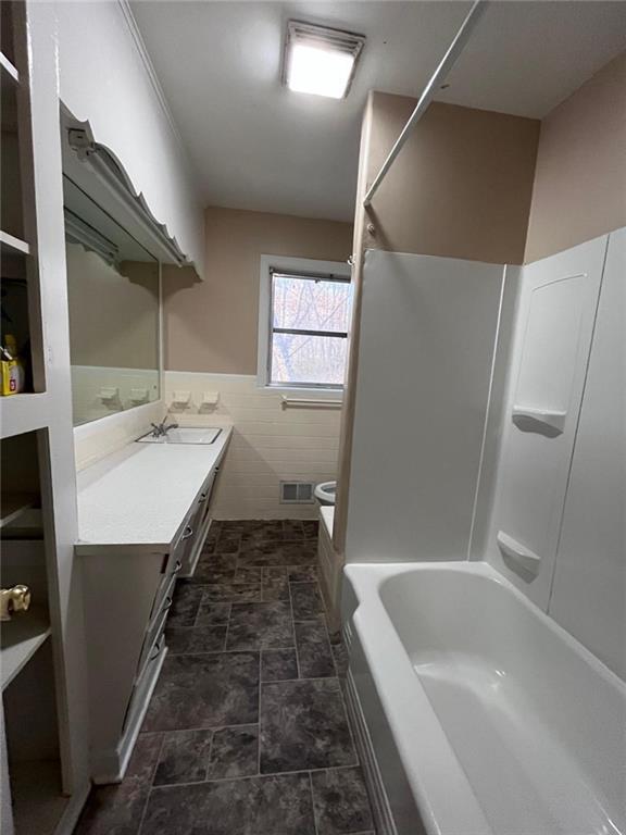 bathroom featuring vanity, tile walls, and toilet