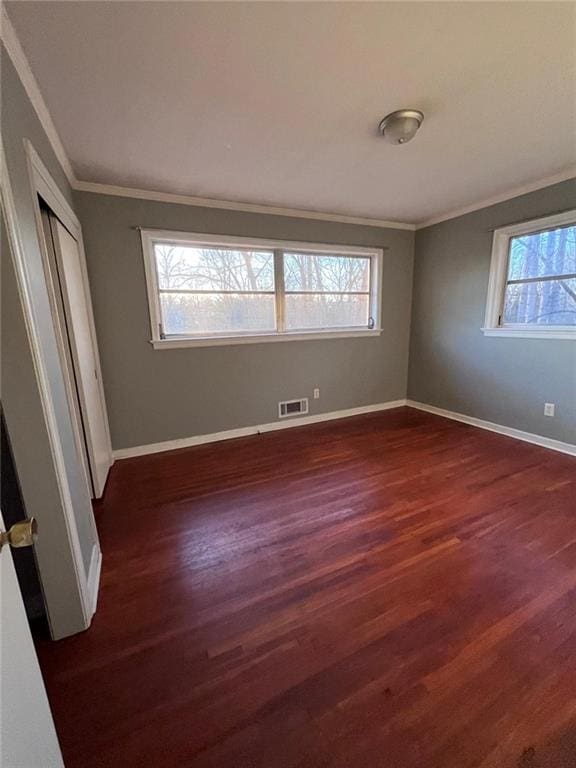 unfurnished bedroom featuring ornamental molding, dark wood-type flooring, and a closet