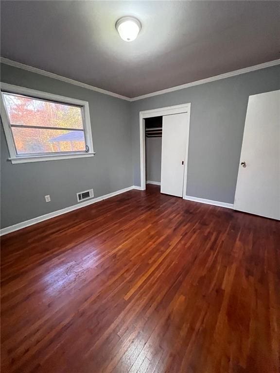 unfurnished bedroom with crown molding, dark hardwood / wood-style floors, and a closet