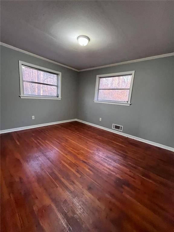 unfurnished room with ornamental molding, plenty of natural light, and dark wood-type flooring