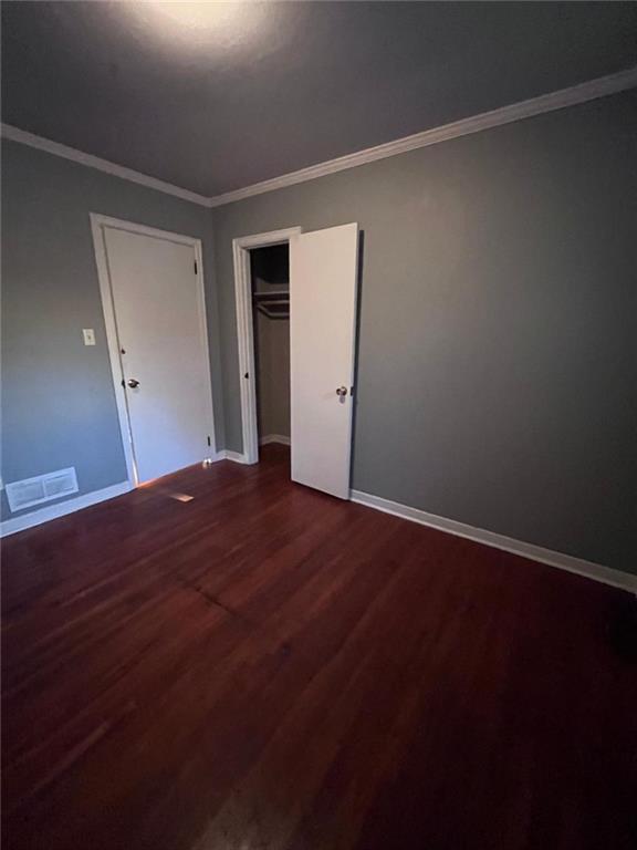 unfurnished bedroom featuring crown molding, hardwood / wood-style flooring, and a closet