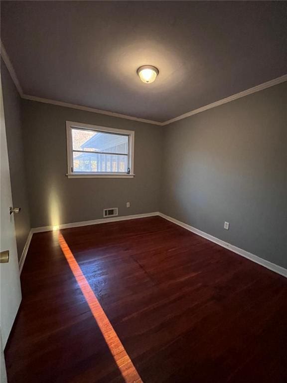 empty room featuring crown molding and dark hardwood / wood-style flooring