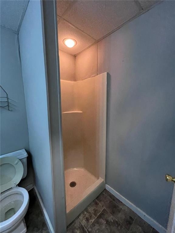 bathroom with a shower, a drop ceiling, and toilet