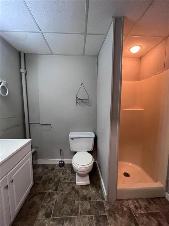 bathroom with vanity, a paneled ceiling, toilet, and walk in shower