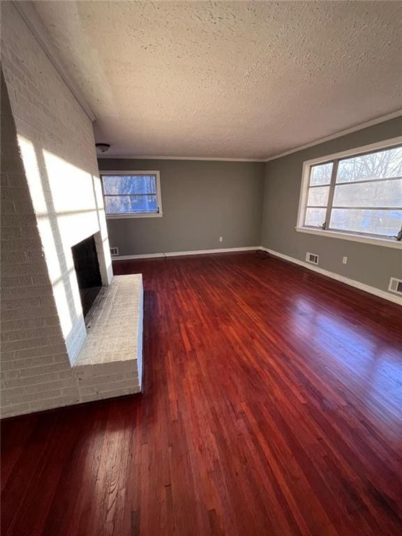unfurnished living room with a textured ceiling, a fireplace, dark hardwood / wood-style floors, and a healthy amount of sunlight