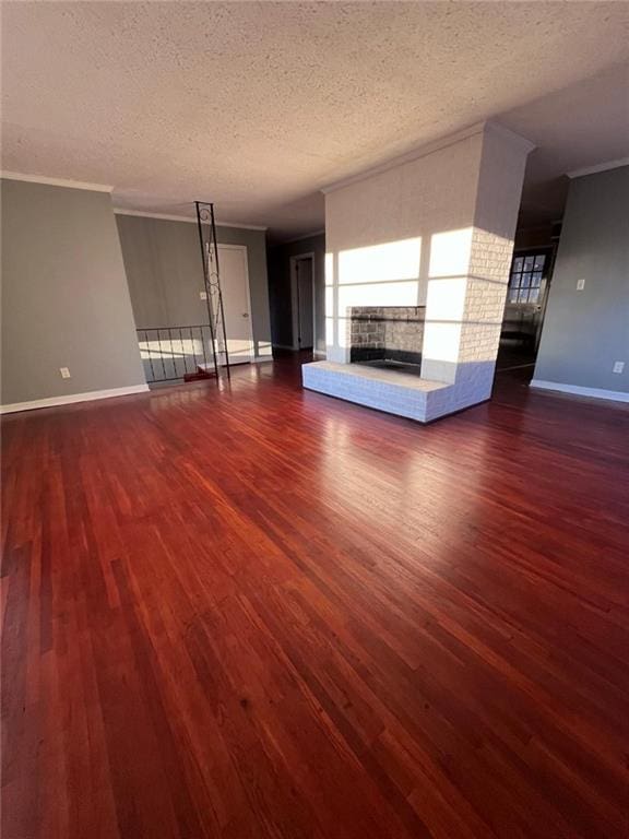 unfurnished living room featuring ornamental molding, a fireplace, dark hardwood / wood-style flooring, and a textured ceiling