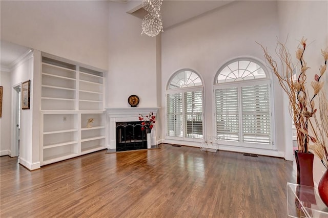 unfurnished living room with baseboards, a fireplace, an inviting chandelier, and wood finished floors