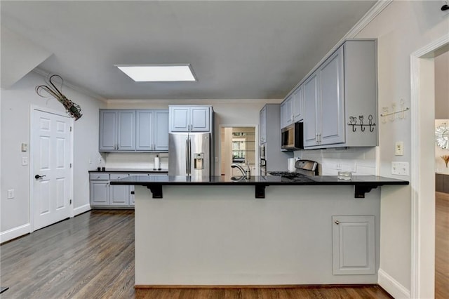 kitchen featuring dark countertops, dark wood-style floors, a peninsula, and stainless steel appliances