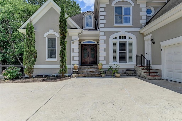 property entrance featuring french doors, an attached garage, and stucco siding