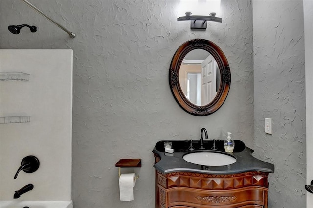 full bathroom with washtub / shower combination, a textured wall, and vanity