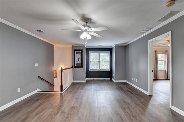 unfurnished room featuring a healthy amount of sunlight, visible vents, and dark wood finished floors