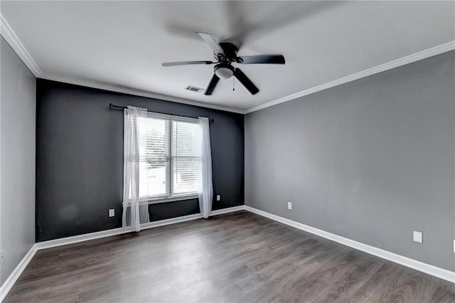 spare room featuring visible vents, ornamental molding, a ceiling fan, wood finished floors, and baseboards