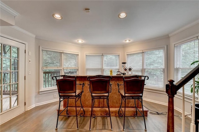 bar with a dry bar, baseboards, and crown molding