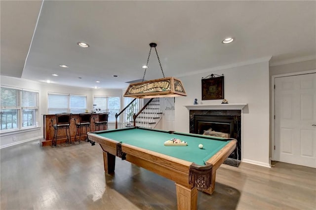 recreation room featuring recessed lighting, billiards, wood finished floors, ornamental molding, and a bar