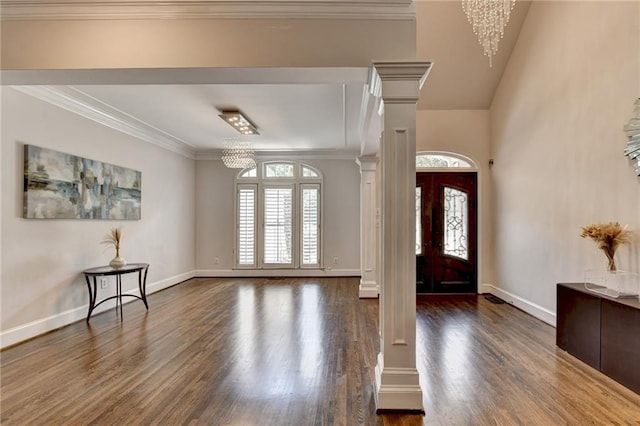 foyer entrance featuring ornate columns, plenty of natural light, ornamental molding, and a notable chandelier