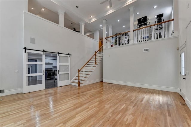 unfurnished living room with stairs, a high ceiling, wood finished floors, and visible vents