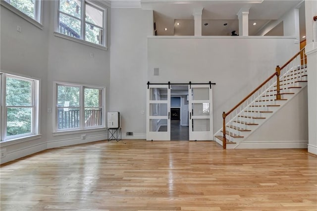 unfurnished living room with a wealth of natural light, wood finished floors, stairway, and a barn door