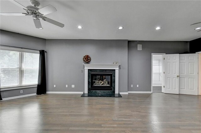 unfurnished living room with recessed lighting, wood finished floors, baseboards, and a premium fireplace